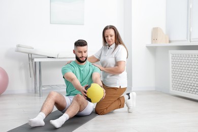 Photo of Doctor and patient exercising with medicine ball in clinic
