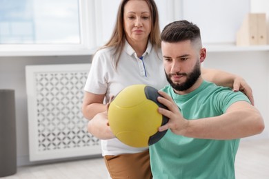 Photo of Doctor and patient exercising with medicine ball in clinic