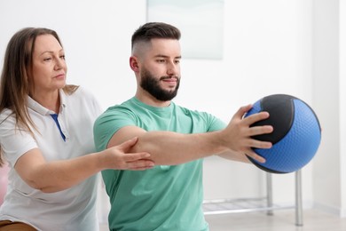 Photo of Doctor and patient exercising with medicine ball in clinic