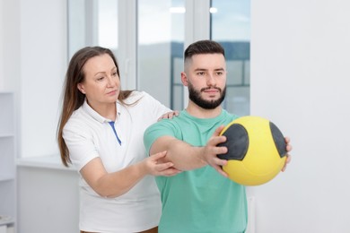 Photo of Doctor and patient exercising with medicine ball in clinic