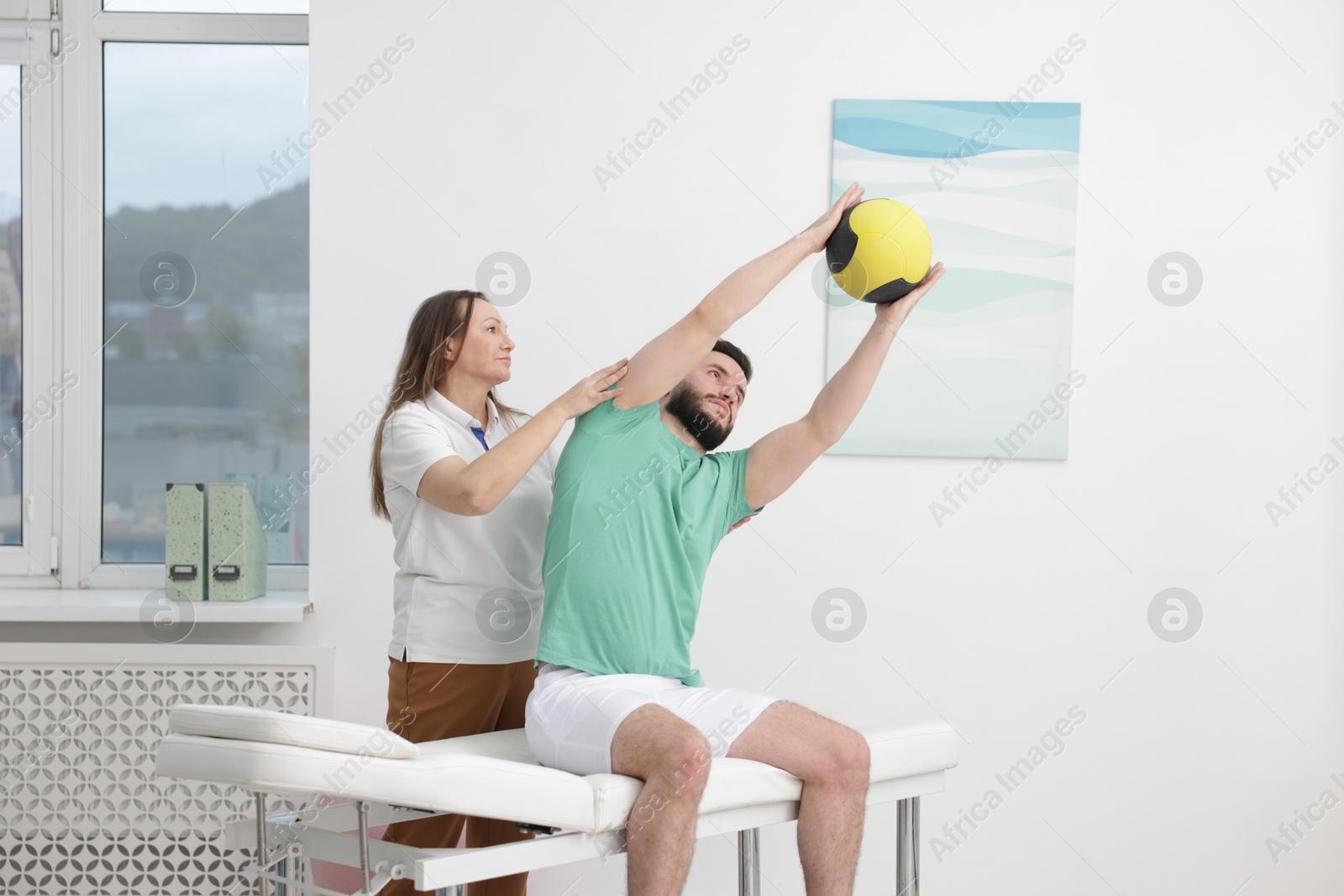 Doctor and patient exercising with medicine ball in clinic Photo of Doctor and patient exercising with medicine ball in clinic