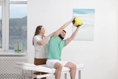 Photo of Doctor and patient exercising with medicine ball in clinic