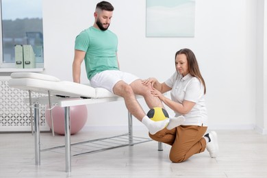 Photo of Doctor and patient exercising with medicine ball in clinic