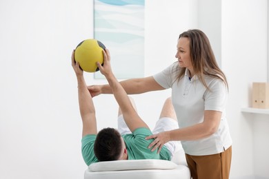 Photo of Doctor and patient exercising with medicine ball in clinic