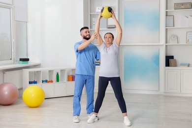 Photo of Doctor and patient exercising with medicine ball in clinic