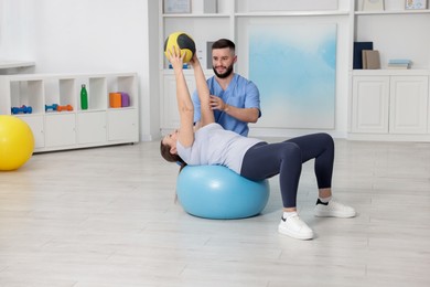 Photo of Doctor and patient exercising with medicine ball in clinic