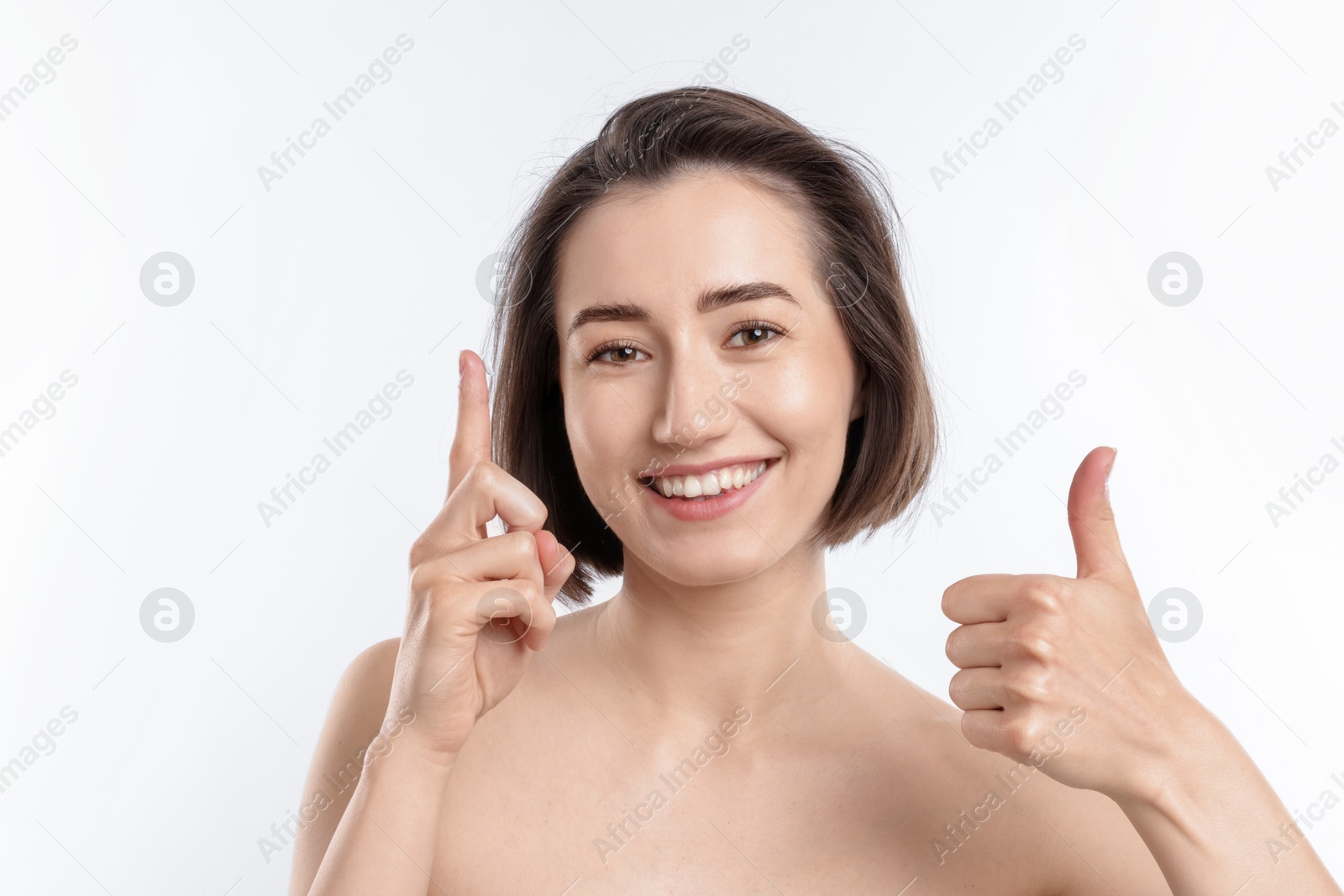 Woman with contact lens showing thumbs up on white background Photo of Woman with contact lens showing thumbs up on white background