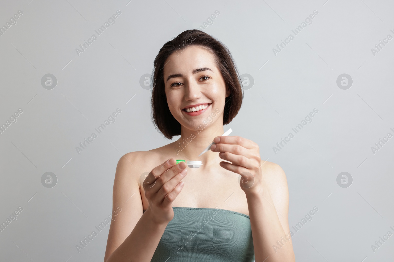 Woman taking contact lens out of case on light background Photo of Woman taking contact lens out of case on light background