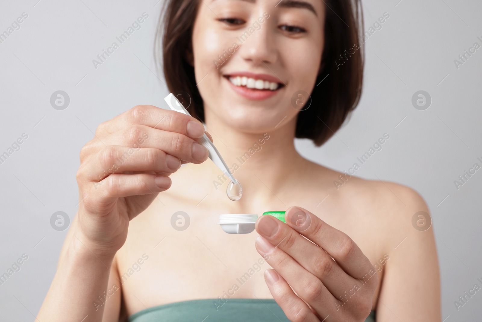 Woman taking contact lens out of case on light background, selective focus Photo of Woman taking contact lens out of case on light background, selective focus