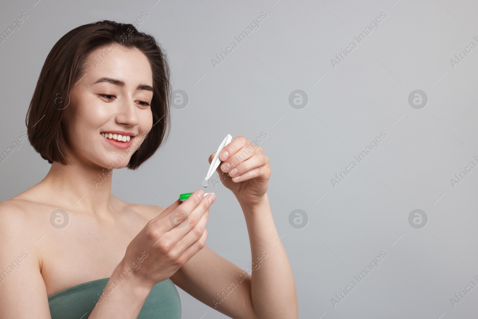 Woman taking contact lens out of case on light background. Space for text Photo of Woman taking contact lens out of case on light background. Space for text