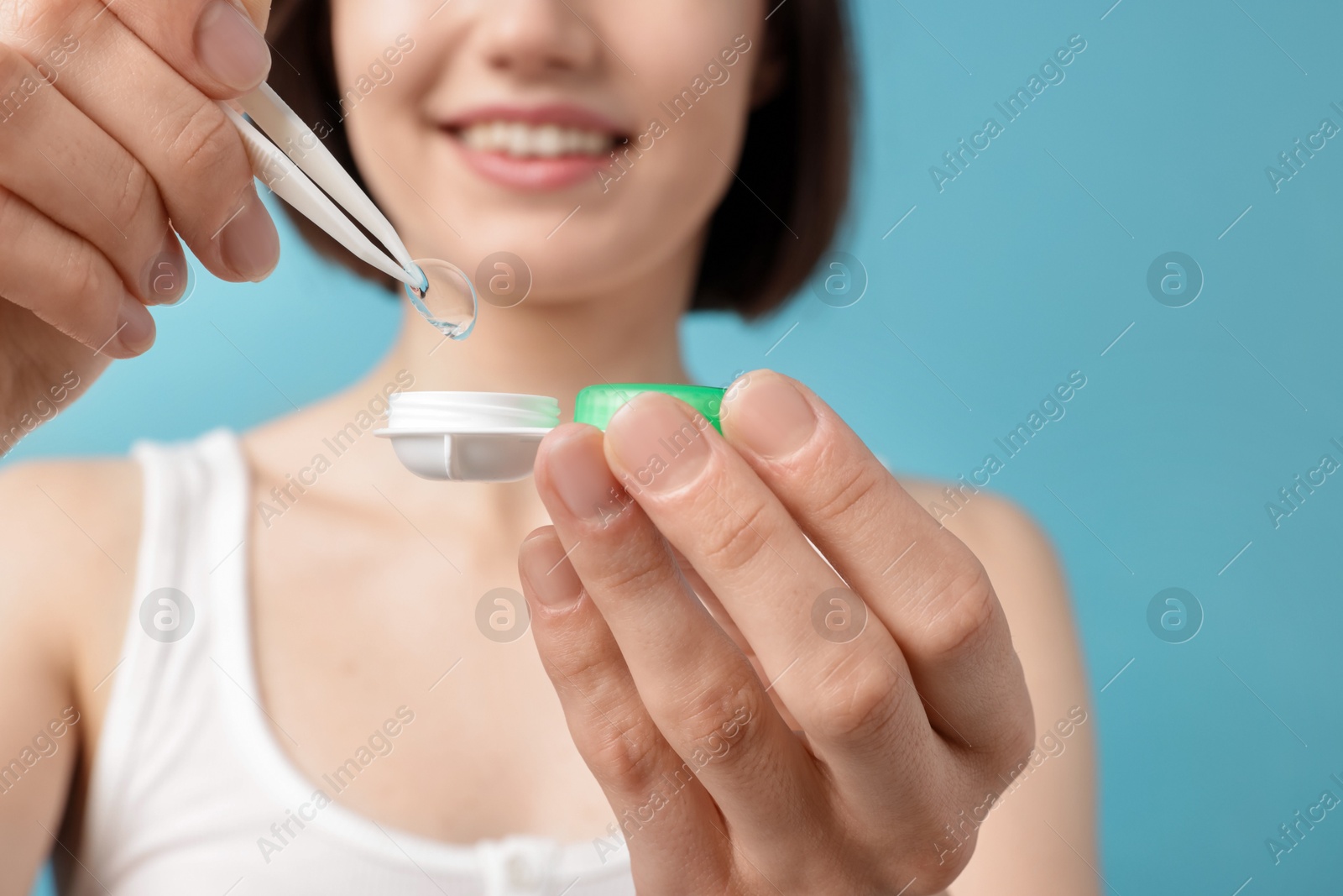 Woman taking contact lens out of case on light blue background, closeup Photo of Woman taking contact lens out of case on light blue background, closeup
