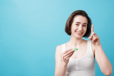 Photo of Woman with contact lens and case on light blue background. Space for text