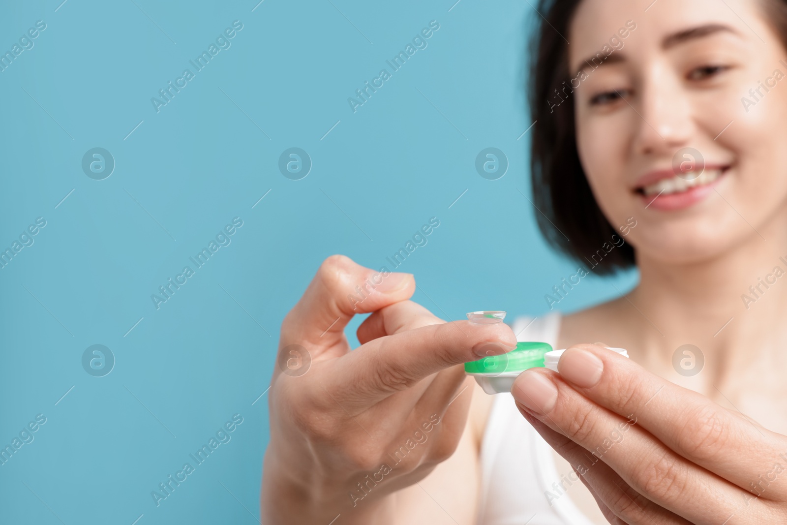 Woman with contact lens and case on light blue background, selective focus. Space for text Photo of Woman with contact lens and case on light blue background, selective focus. Space for text
