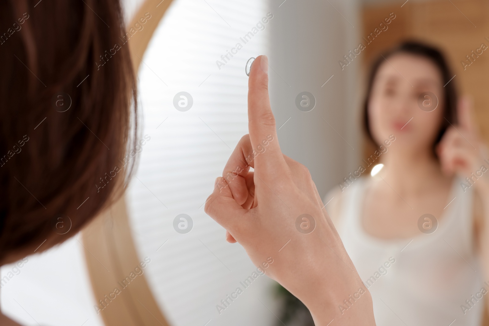 Woman with contact lens near mirror indoors, selective focus Photo of Woman with contact lens near mirror indoors, selective focus