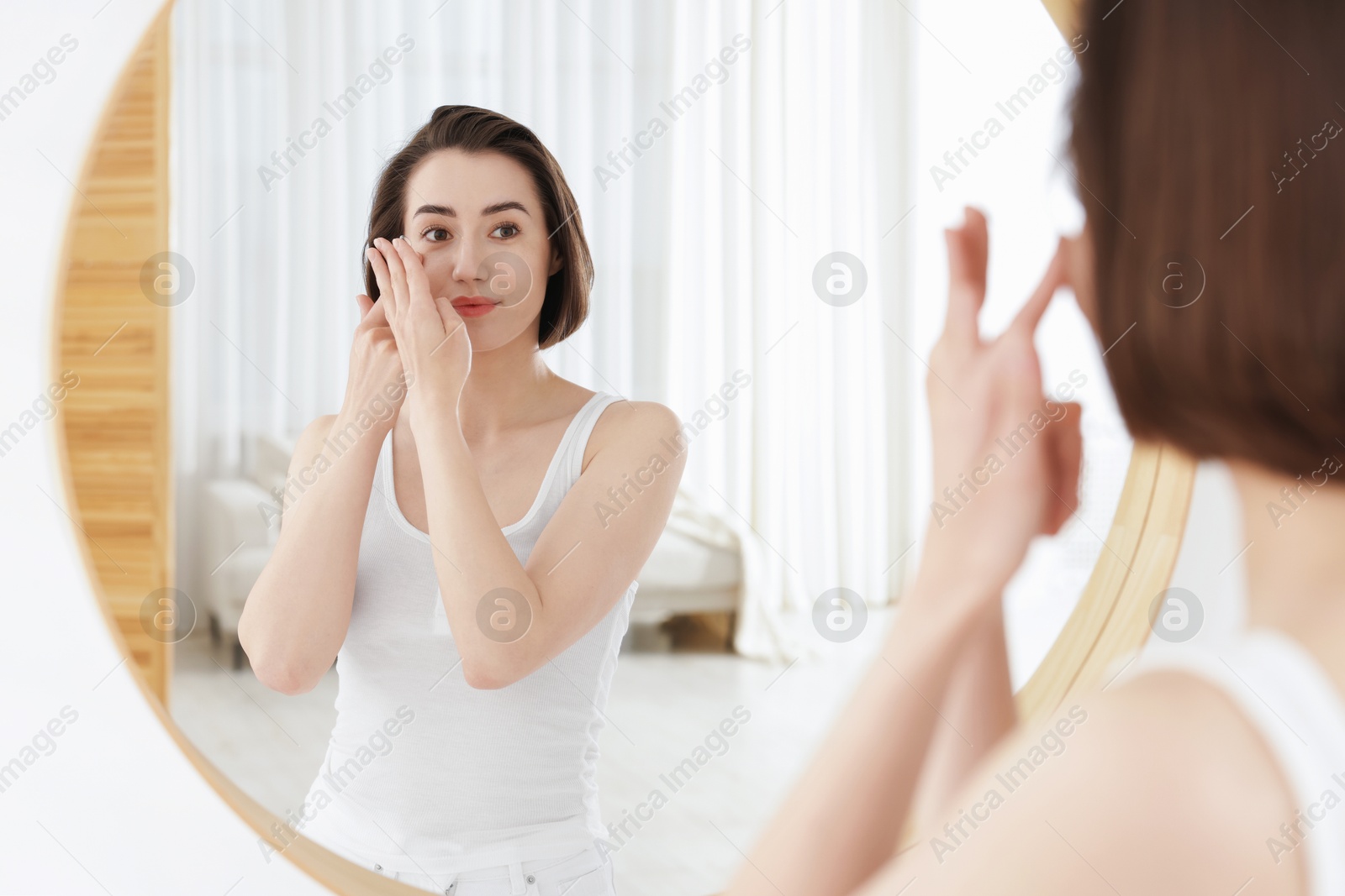 Woman putting in contact lens near mirror indoors Photo of Woman putting in contact lens near mirror indoors