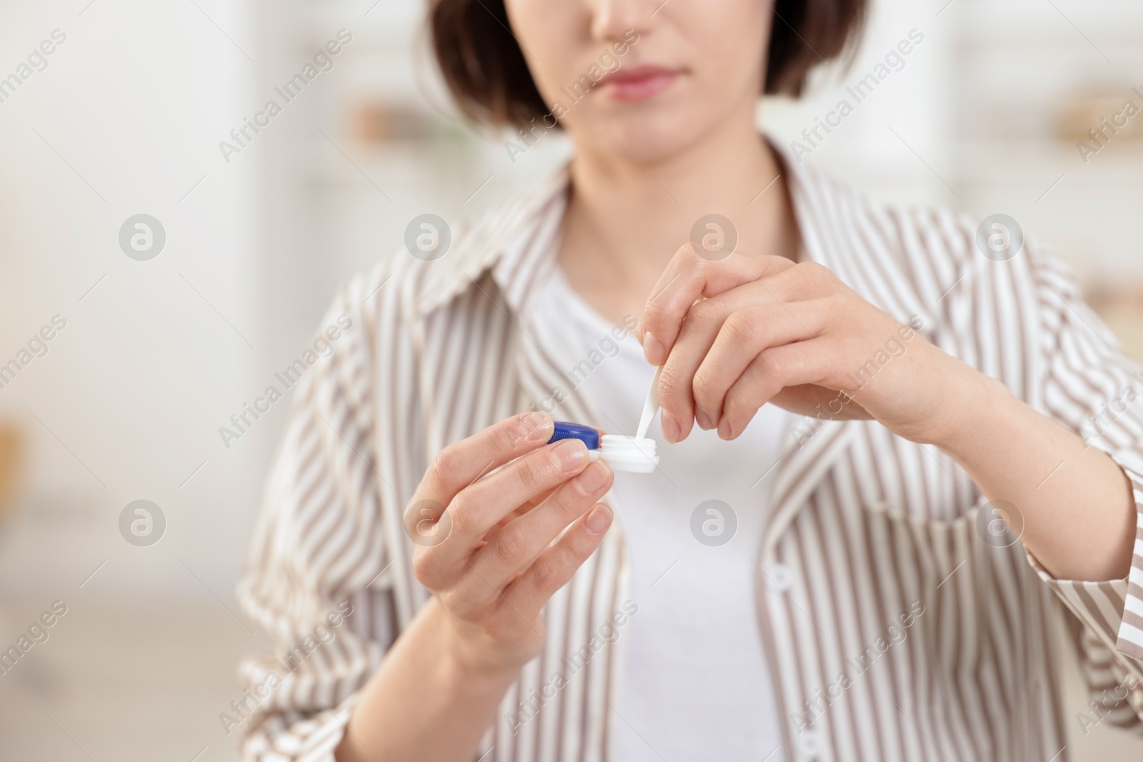 Woman taking contact lens out of case indoors, closeup Photo of Woman taking contact lens out of case indoors, closeup