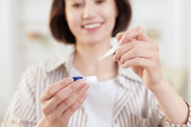 Photo of Woman taking contact lens out of case indoors, closeup