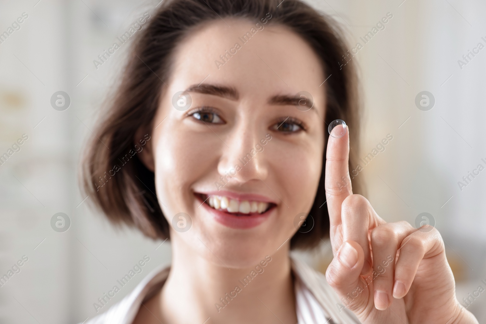 Happy woman with contact lens on her finger indoors Photo of Happy woman with contact lens on her finger indoors