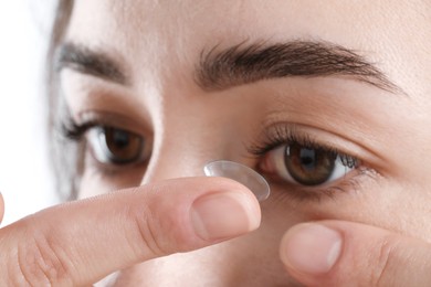 Photo of Woman putting in contact lens on white background, closeup