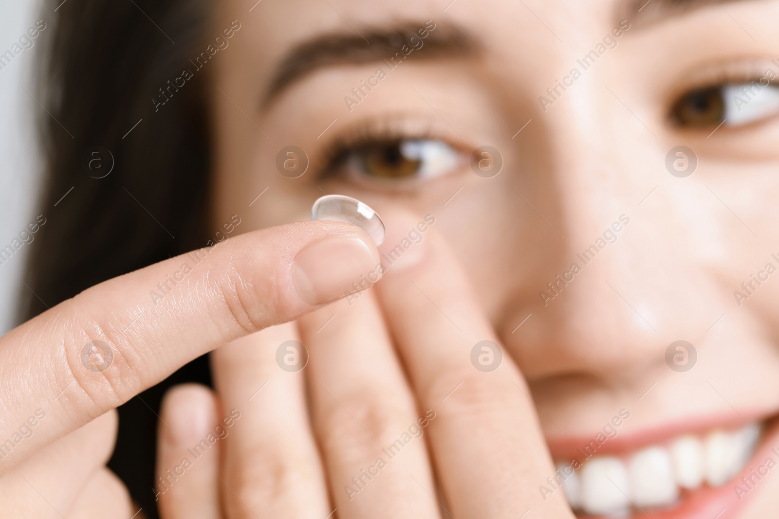 Woman putting in contact lens on light background, closeup Photo of Woman putting in contact lens on light background, closeup