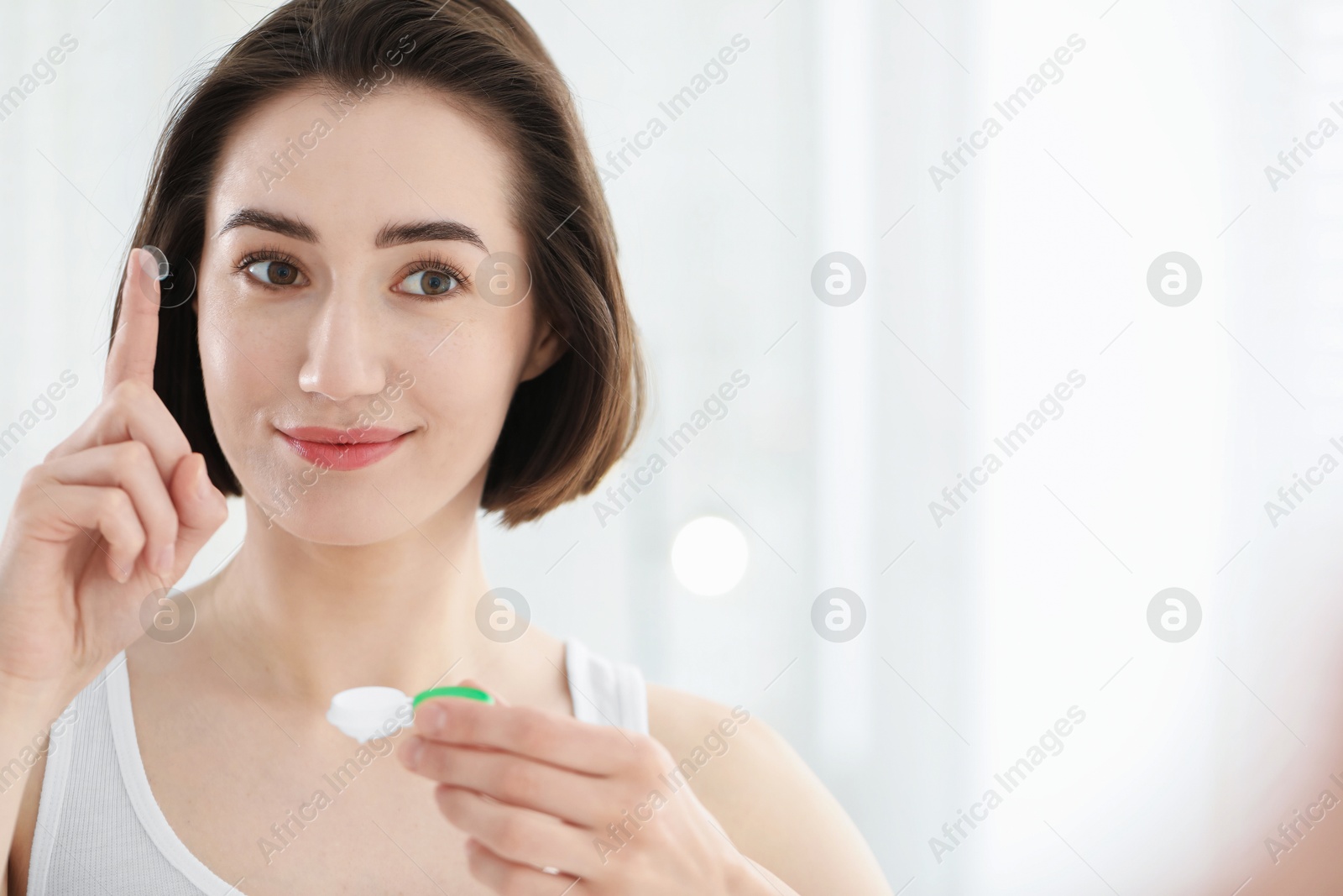 Photo of Woman with contact lens and case indoors. Space for text