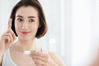 Photo of Woman with contact lens and case indoors. Space for text