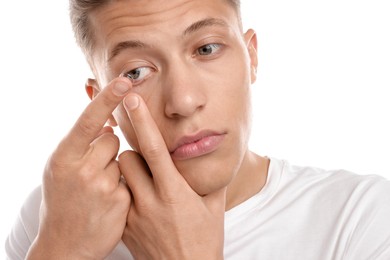 Photo of Man putting in contact lens on white background, closeup