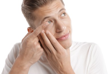 Photo of Man putting in contact lens on white background