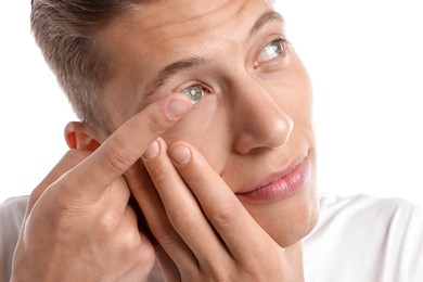 Photo of Man putting in contact lens on white background, closeup