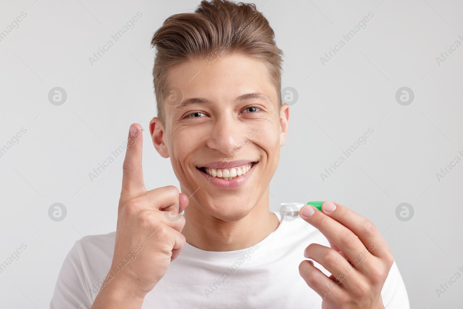 Man with contact lens and case on light background Photo of Man with contact lens and case on light background