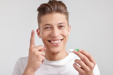 Photo of Man with contact lens and case on light background