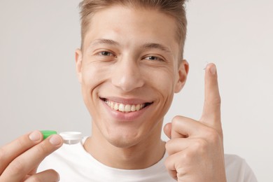 Photo of Man with contact lens and case on light background