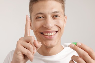 Photo of Man with contact lens and case on light background