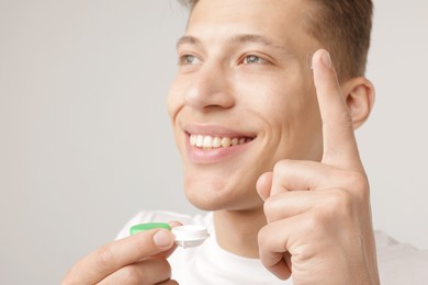 Photo of Man with contact lens and case on light background, closeup