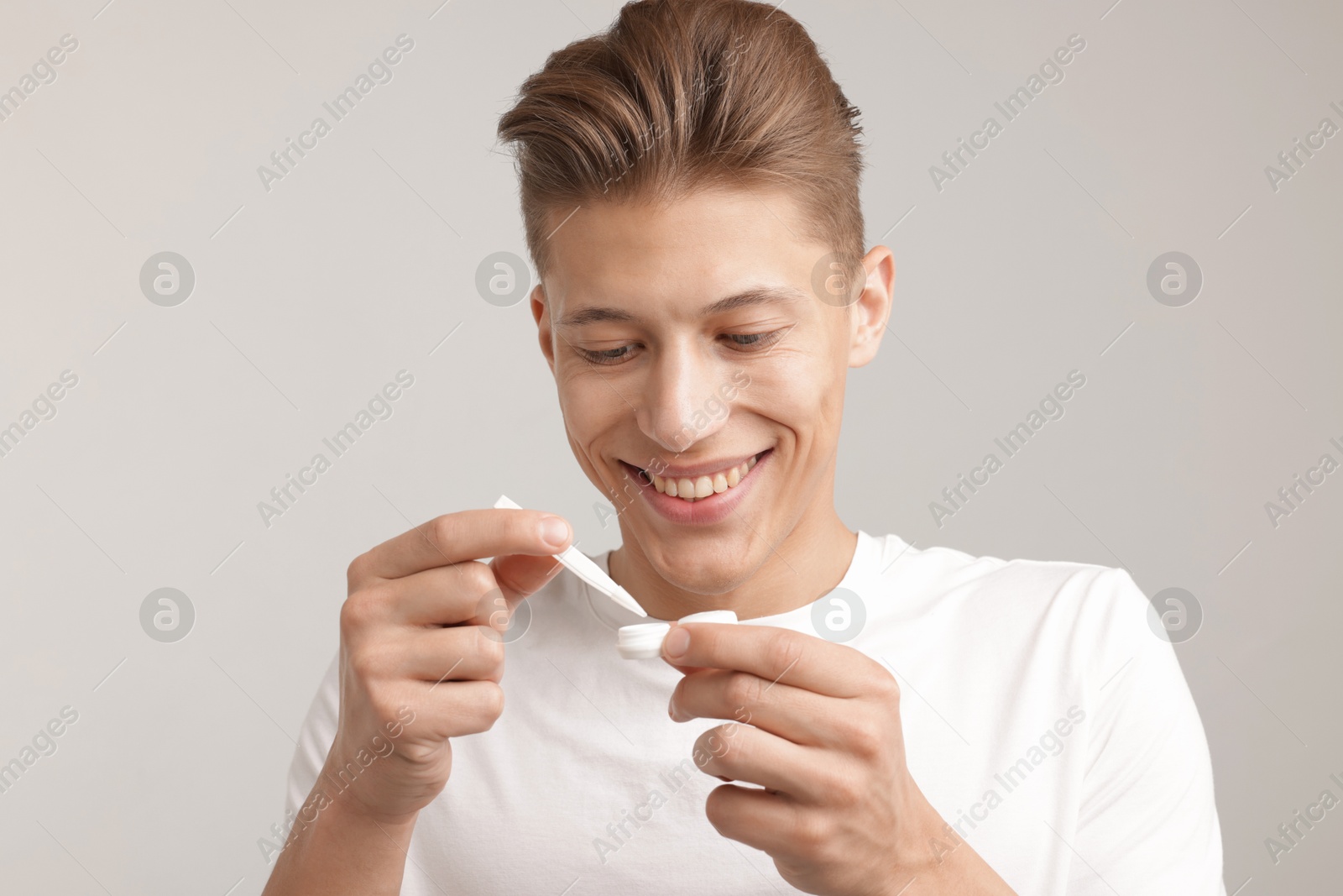 Man taking contact lens out of case on light background Photo of Man taking contact lens out of case on light background