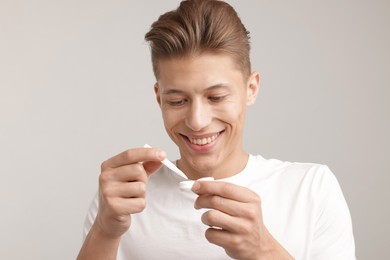 Photo of Man taking contact lens out of case on light background