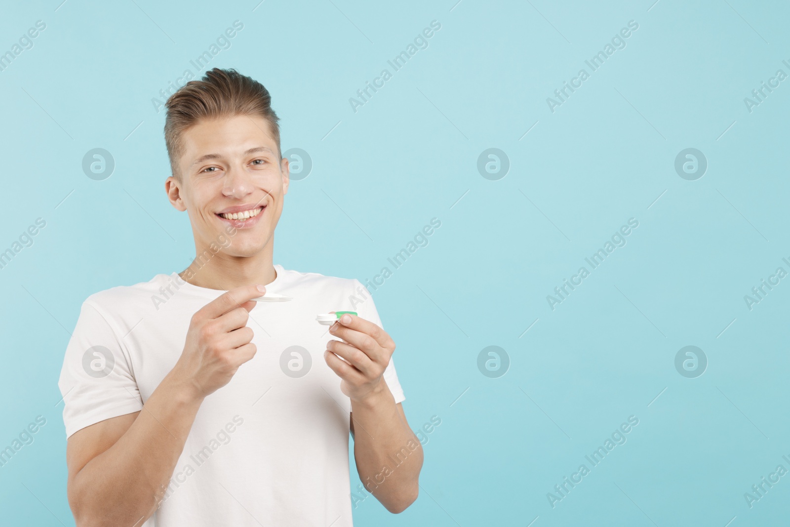 Man with contact lens and case on light blue background. Space for text Photo of Man with contact lens and case on light blue background. Space for text