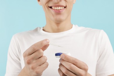 Photo of Man with contact lens and case on light blue background, closeup