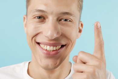 Photo of Man with contact lens on light blue background, closeup