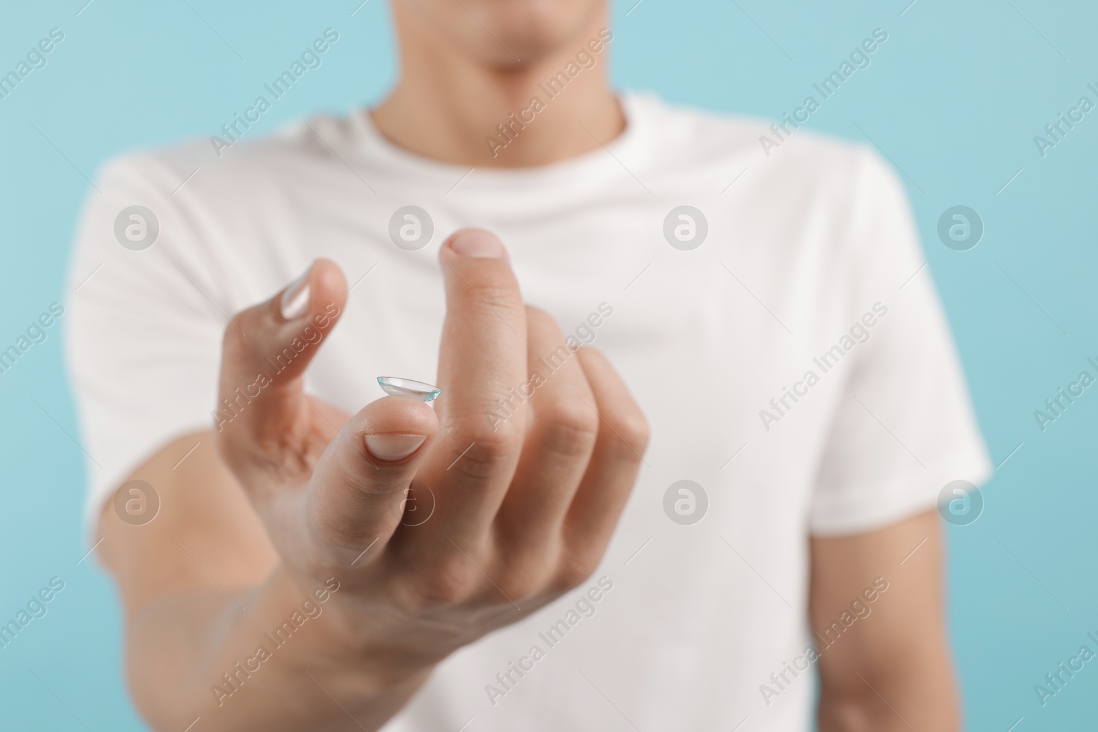 Man with contact lens on light blue background, closeup Photo of Man with contact lens on light blue background, closeup