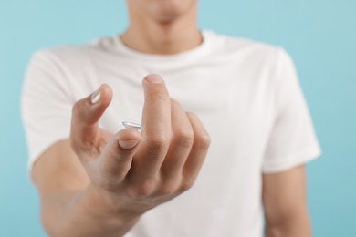 Photo of Man with contact lens on light blue background, closeup