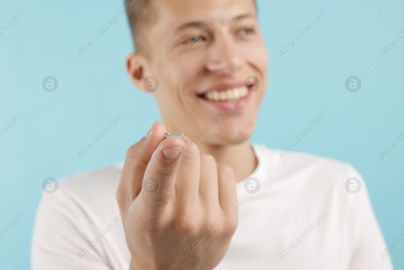 Man with contact lens on light blue background, selective focus Photo of Man with contact lens on light blue background, selective focus