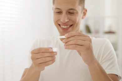 Photo of Man taking contact lens out of case at home, selective focus