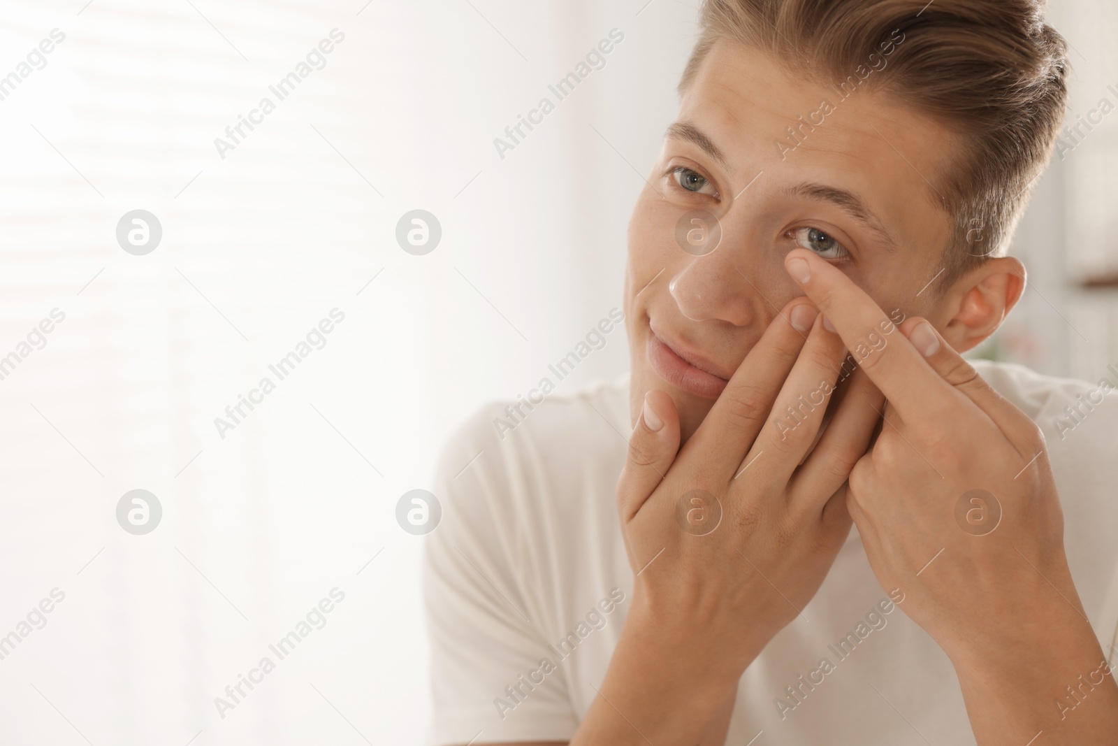 Man putting in contact lens at home. Space for text Photo of Man putting in contact lens at home. Space for text