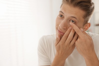 Photo of Man putting in contact lens at home. Space for text