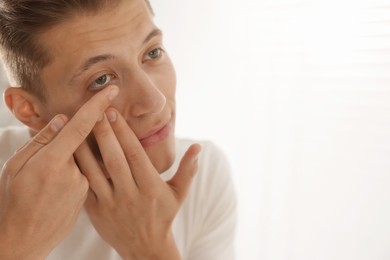 Photo of Man putting in contact lens at home. Space for text