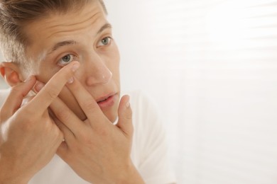 Photo of Man putting in contact lens at home, closeup. Space for text