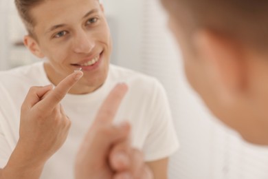 Photo of Man putting in contact lens near mirror at home