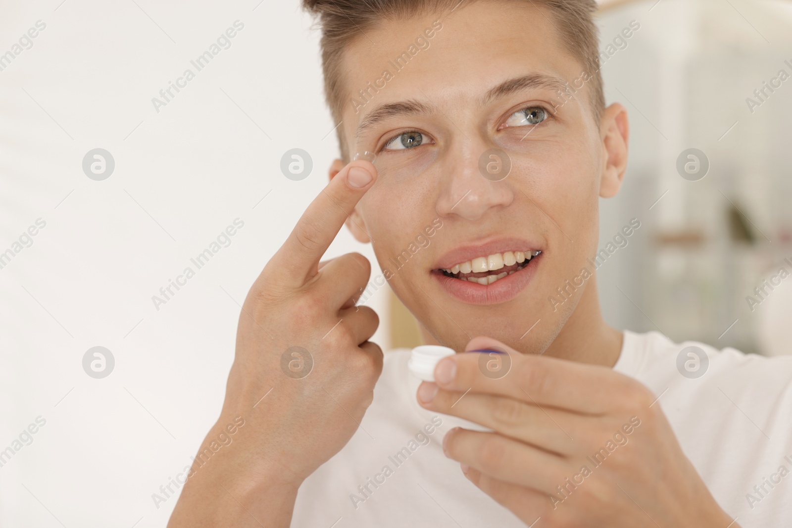Man putting in contact lens at home Photo of Man putting in contact lens at home