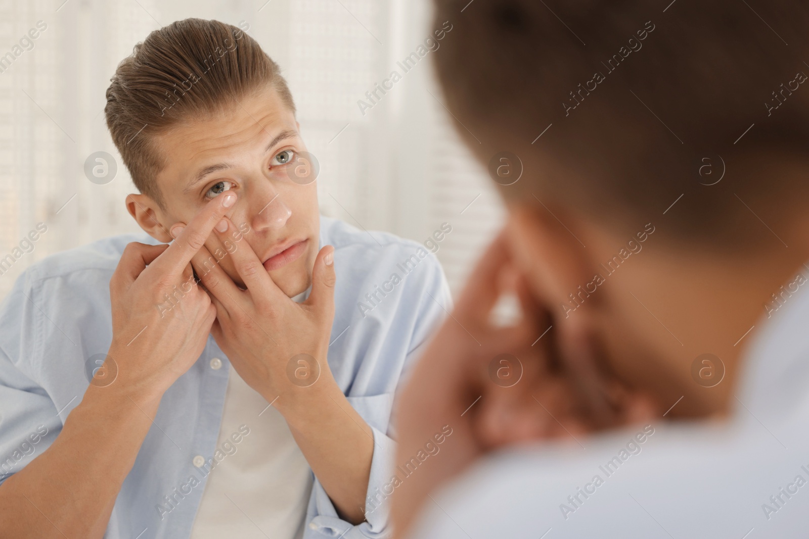 Man putting in contact lens near mirror at home Photo of Man putting in contact lens near mirror at home